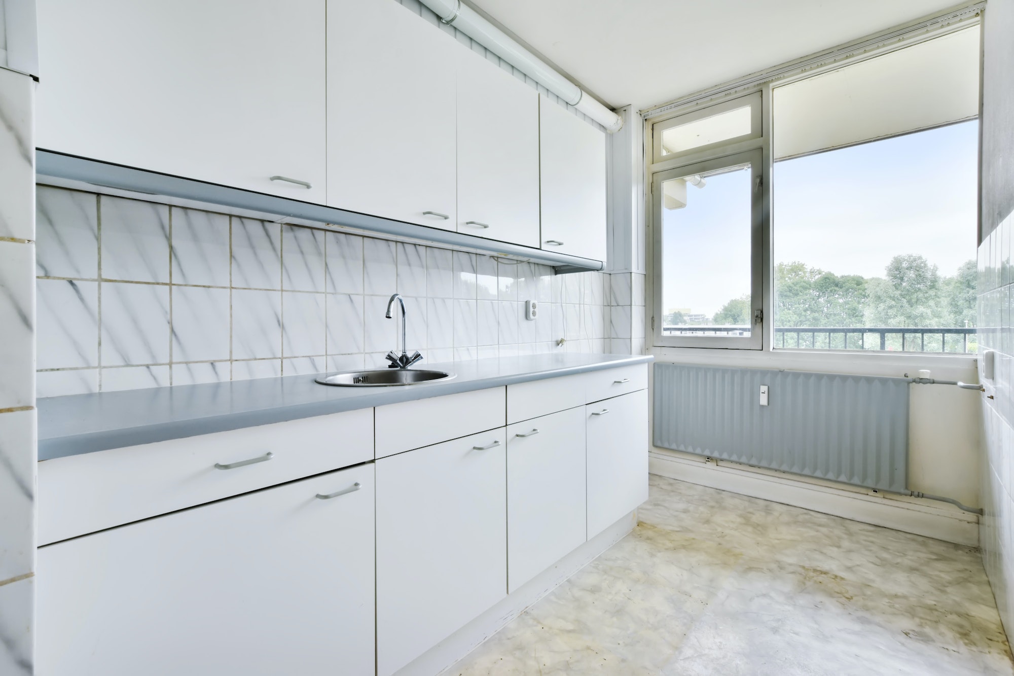 An empty and bright kitchen with a white kitchen set